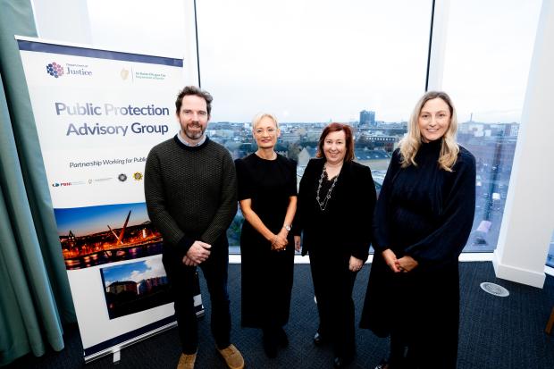 Ulster University's Dr Brian Payne, Probation Board for Northern Ireland Chief Executive Amanda Stewart, The Probation Service Director (Acting) Una Doyle standing in front of a large window with the Public Protection Advisory Group pop-up